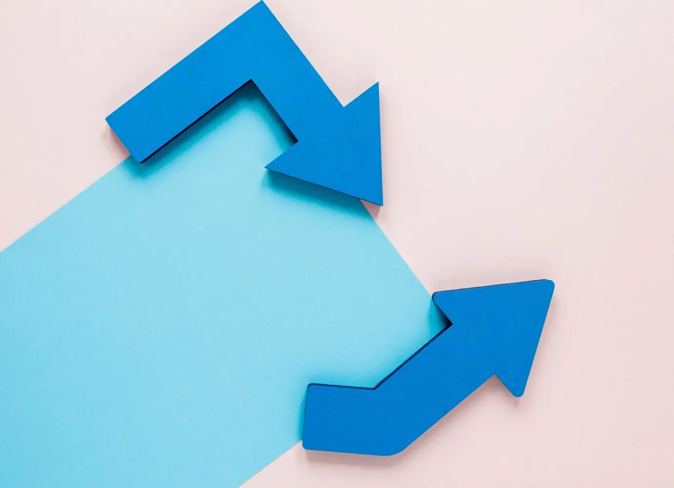 Draufsicht auf blaue Pfeile und ein blaues Pappmodell auf pinkem Hintergrund.